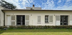Edifici de planta baixa amb teulada plana, parets exteriors blanques i diverses finestres amb persianes.