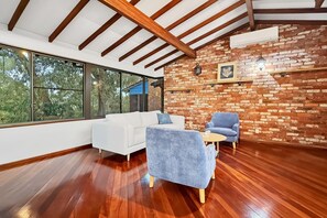Una sala de estar moderna con un sofá blanco, un sillón azul y una pared de ladrillo.