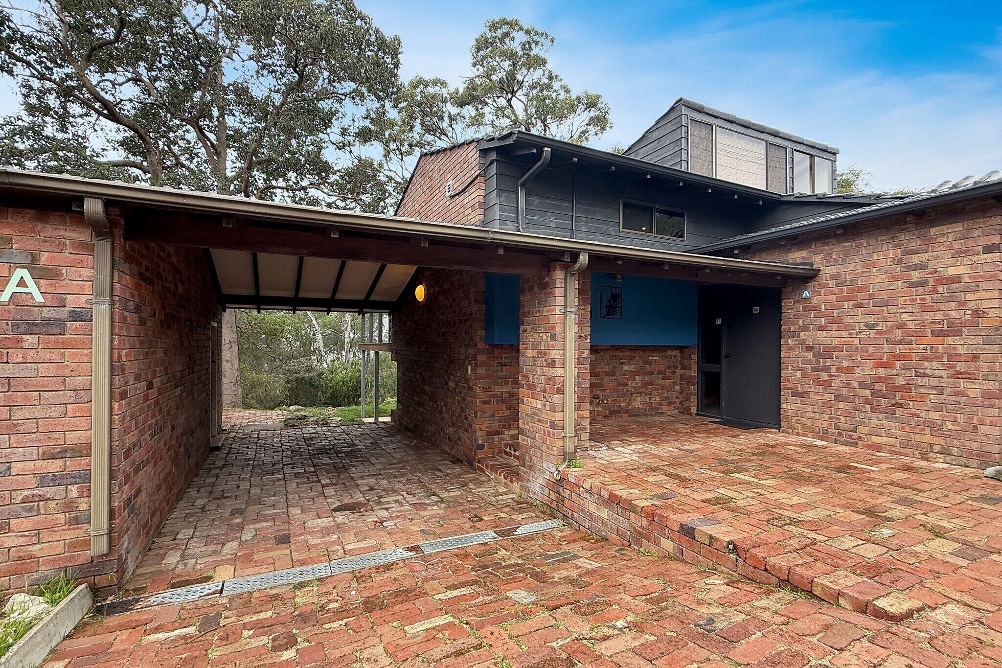 A brick building with a covered outdoor area, a garage, and a second-story structure.