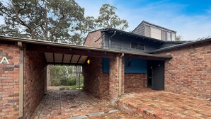 Un bâtiment en briques doté d’un espace extérieur couvert, d’un garage et d’une structure à l’étage.
