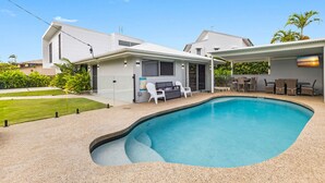 Une maison moderne dotée d’une piscine, d’un espace salon extérieur et d’une pelouse bien entretenue.