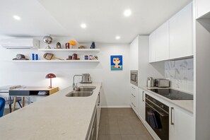 Een moderne keuken met witte kastjes, een centraal eiland, een spoelbak en een magnetron.