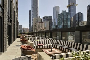 En tagterrasse med udendørs møbler, udsigt over byens skyline og moderne arkitektur.