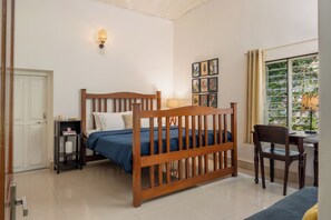 Une chambre à coucher avec un lit en bois, un bureau, une chaise, une lampe et un luminaire fixé au mur.