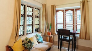 Una habitación con sofá, mesa de comedor y una planta en maceta.