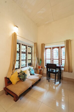 A room with a sofa, a dining table, and a potted plant.