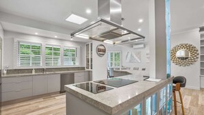 A modern kitchen with a central island, built-in appliances, and a view of the outdoors. - Spacious 7-Bed Family Home in Chapel Hill (Chapel Hill)