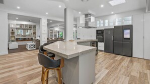A modern kitchen with a central island, built-in appliances, and a dining area with bar stools. - Spacious 7-Bed Family Home in Chapel Hill (Chapel Hill)