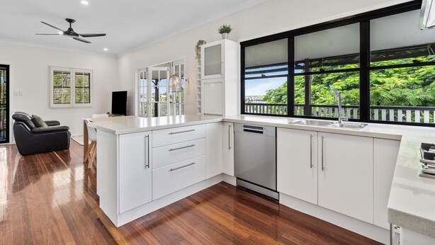 A modern kitchen with white cabinetry, a built-in dishwasher, and a large window with a view of greenery. - Relaxing Stay Near Brisbane’s Cultural Heart (Norman Park)