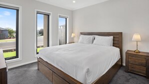 Een slaapkamer met een groot bed, twee nachtkastjes en uitzicht op buiten.