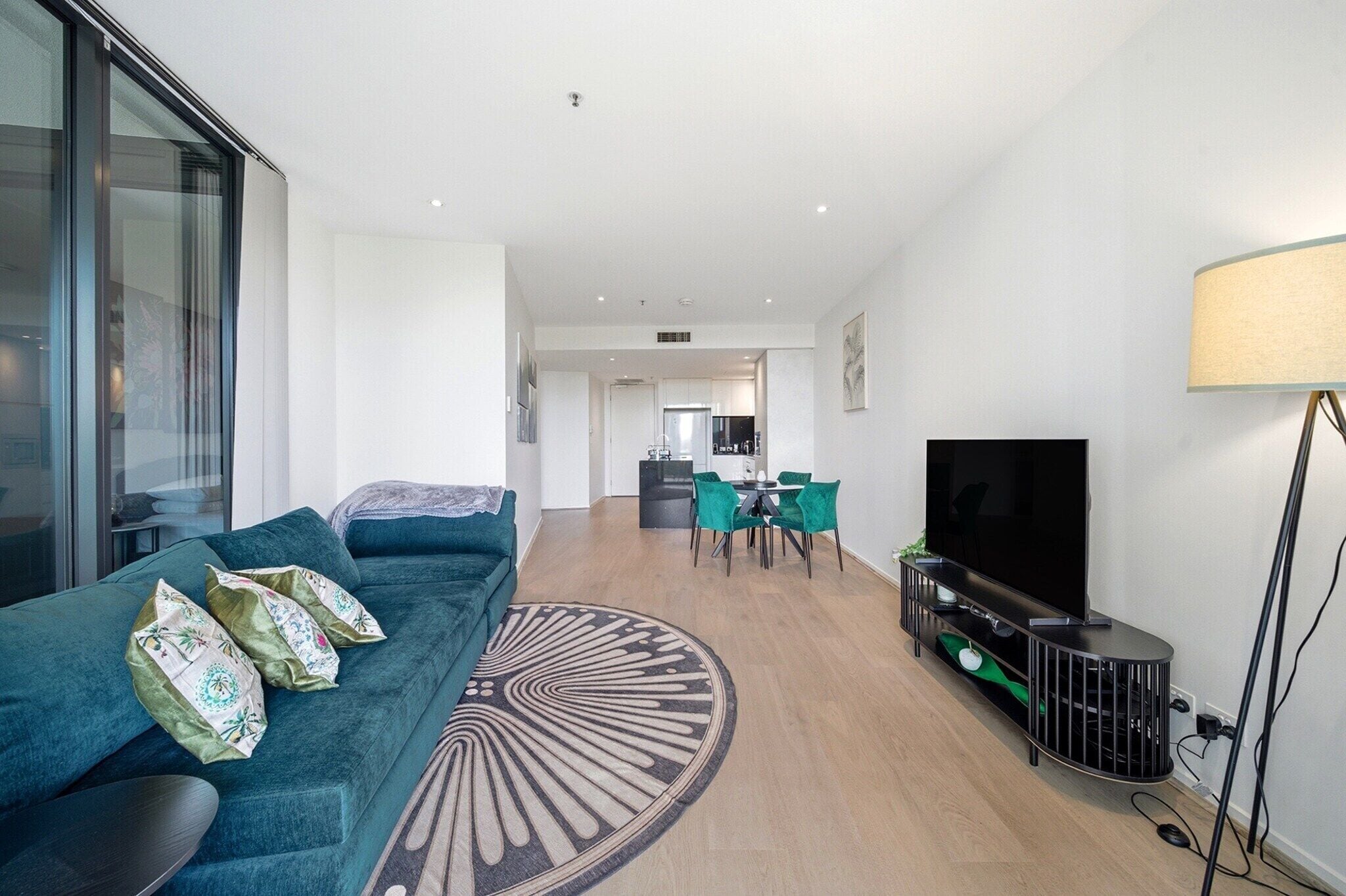 A modern living room with a sofa, TV, and dining area.