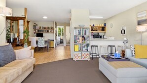 Uma sala moderna com sofá, mesa de centro, estante de livros, área de refeições e cozinha.
