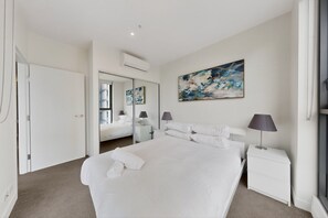 Een moderne hotelkamer met een groot bed, nachtkastjes, een spiegel en een schilderij aan de muur.