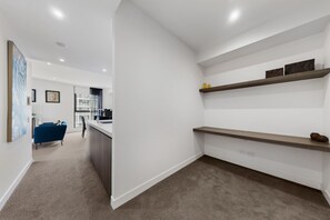 Een modern interieur met een keukenhoek, een blauwe bank en een witte muur met planken.