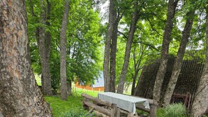 A rustic outdoor setting with a wooden bench, a metal table, and a fence. - Apartments Javorje- Alpine Atelier Studio (Žabljak)