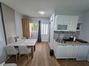 A compact kitchen with white cabinets, a sink, and a dining area with a table and chairs.