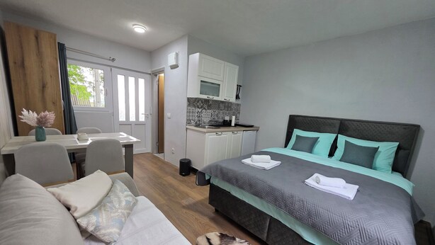 A bedroom with a bed, a small kitchenette, a dining area, and a view of the outdoors. - Apartments Javorje- Alpine Atelier Studio (Žabljak)