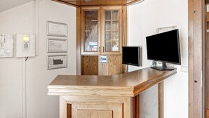 En receptionsdisk med en platt-TV, träskåp och inramade arkitektoniska ritningar på väggen.