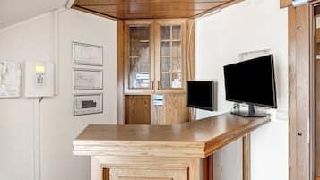 A reception desk with a flat-screen TV, wooden cabinets, and framed architectural plans on the wall.