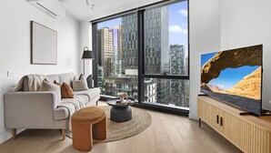 Un salon moderne avec une grande fenêtre, un canapé, une table basse et un téléviseur.
