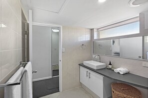 Ein modernes Badezimmer mit Dusche, Waschbecken, Spiegel und Handtuchhalter.