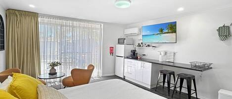 Ein Hotelzimmer mit einem Bett, einem Schreibtisch mit Computer, einem Fernseher und einem Fenster mit Vorhängen.
