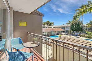 A balcony with blue chairs, a small table, and a warning sign. - Charming Studio Apartment in Mandurah (Mandurah)