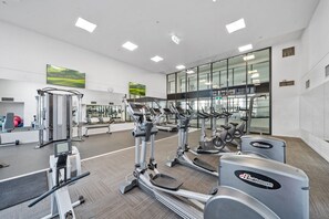 Een fitnessruimte met cardioapparatuur, gewichten en een groot raam.