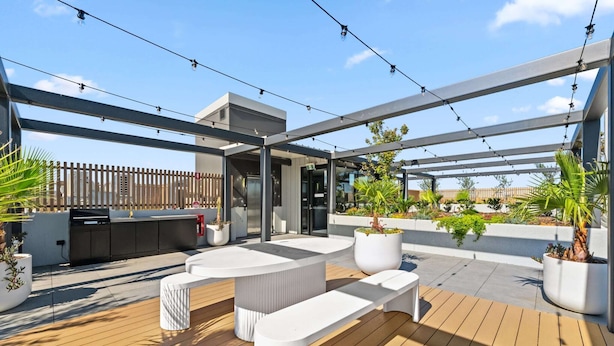 Eine Terrassenanlage mit integrierter Küche, Sitzgelegenheiten und Kübelpflanzen.