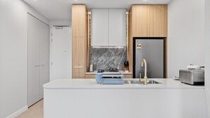 Eine moderne Küche mit einer zentralen Kochinsel, eingebauten Schränken, einem Edelstahlkühlschrank und einem Gasherd.