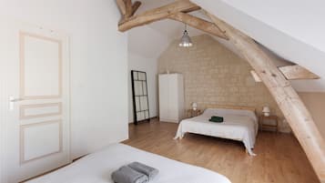 A bedroom with a sloped ceiling, a bed, a wardrobe, and a bedside table.
