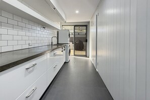 A modern kitchen with white cabinetry, a built-in oven, and a stainless steel sink. - Comfortable Stay Near Busselton Beach (West Busselton)