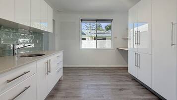A modern kitchen with white cabinets, a large window, and a view of a house.