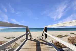 A wooden boardwalk leading to a beach with clear skies.