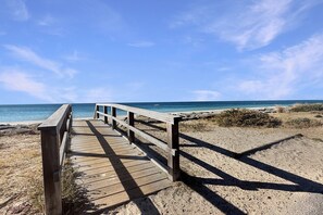 A wooden boardwalk leading to a beach with clear skies.