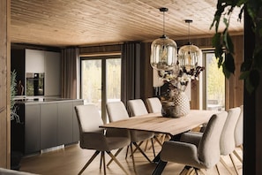 Un comedor moderno con una mesa de madera, sillas tapizadas e iluminación colgante.