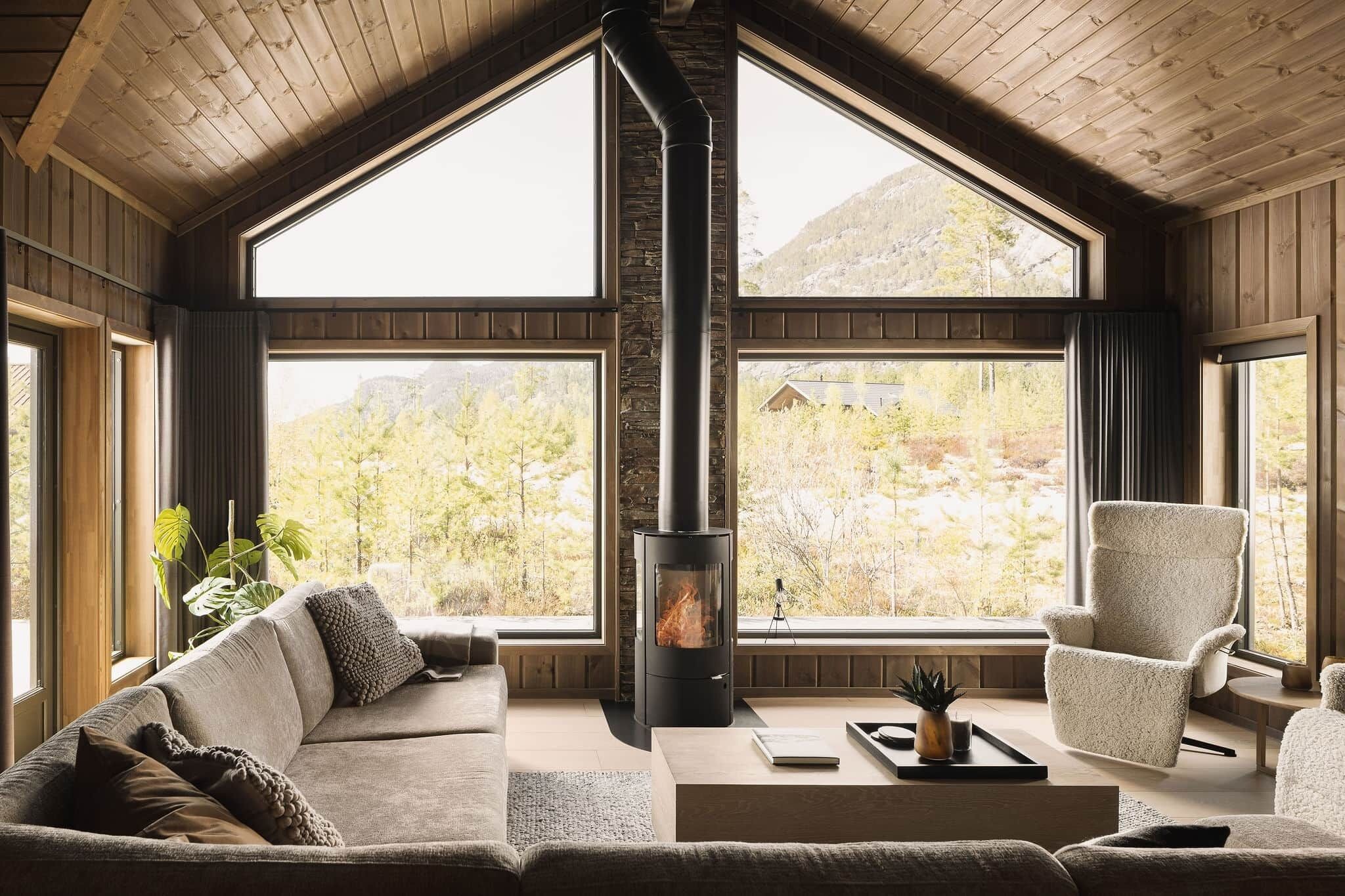 A cozy room with a fireplace, large windows, a sofa, and a chair.. Det Kosekroken with jacuzzi