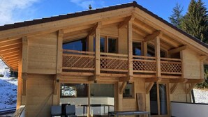 A wooden chalet with a balcony, large windows, and a dining area. - Chalet La Centaurée - by Care Concierge (Combloux)
