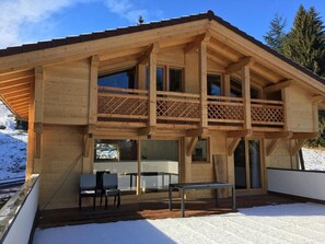 A wooden chalet with a balcony, large windows, and a dining area. - Chalet La Centaurée - by Care Concierge (Combloux)