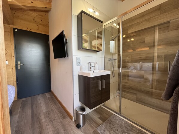 Un baño moderno con ducha de vidrio, un lavabo y un espejo.