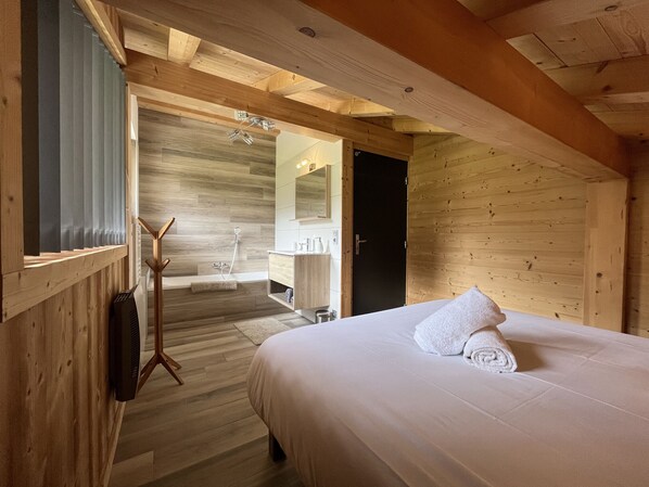 A wooden cabin interior with a bed, a bathroom with a shower, and a wooden ceiling. - Chalet La Centaurée - by Care Concierge (Combloux)