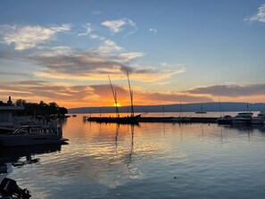 A marina with boats docked, calm water, and a sunset in the background. - The Blue Grotto. Stay on the blue shores of Lake Geneva, in the heart of the Alps. (Évian-les-Bains)