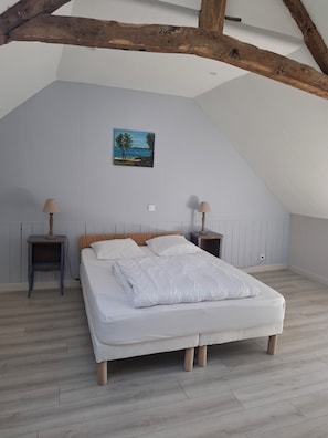 A bedroom with a bed, two nightstands, a painting, and exposed wooden beams. - Large family home with swimming pool (Saint-Lormel)