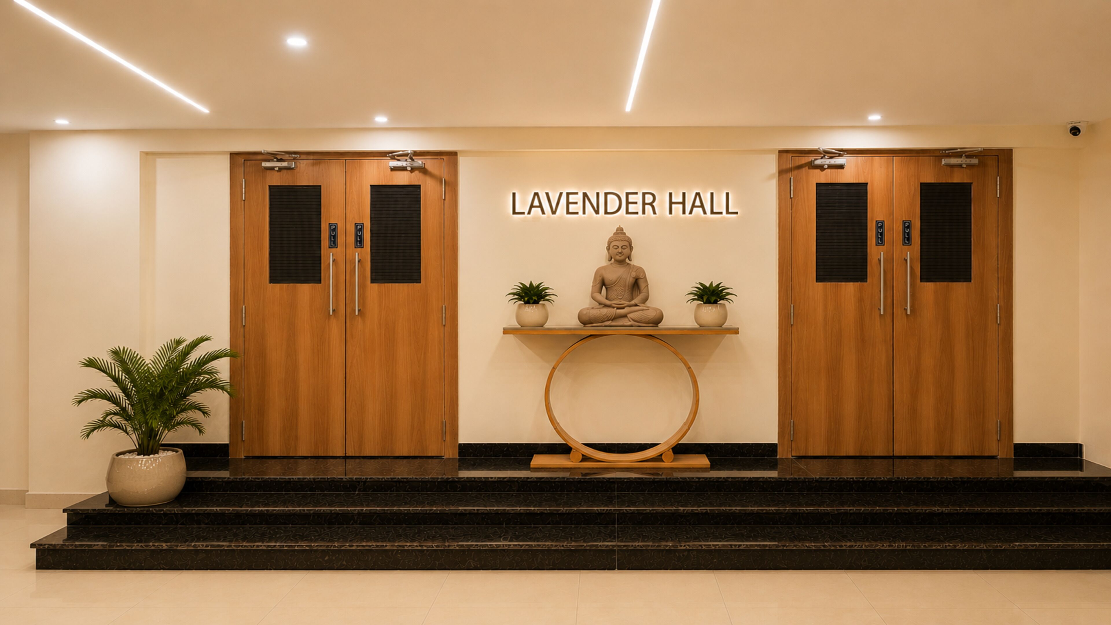 A reception area with a sign reading 'LAVENDER HALL,' two wooden doors, a Buddha statue, and a small table with potted plants.