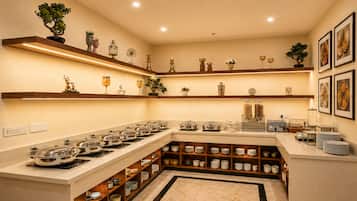 A well-lit kitchen with multiple burners, a variety of bowls and plates, and decorative items on shelves.