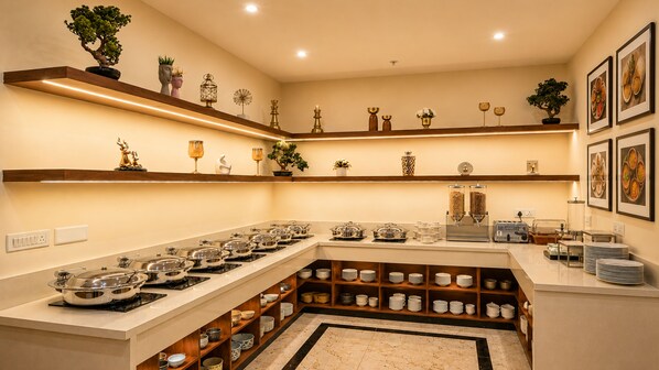 A well-lit kitchen with multiple burners, a variety of bowls and plates, and decorative items on shelves.