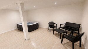 Una habitación amplia con jacuzzi, un sofá y dos sillones.