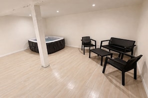 Et rummeligt værelse med jacuzzi, en sofa og to lænestole.