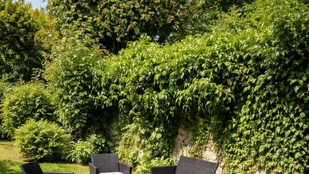 Un patio con mobiliario exterior, incluyendo una mesa, sillas y una tumbona.