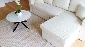 Una sala de estar con un sofá blanco, una mesa de centro redonda y un tapete estampado.